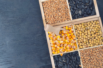 Small box with various grains and cereals on wooden table, top view, copy space