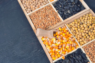 Small box with various grains and cereals on wooden table, top view, copy space