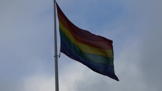 Rainbow flag in the city center. Rainbow flag (LGBT movement) fluttering in the wind. Close-up.