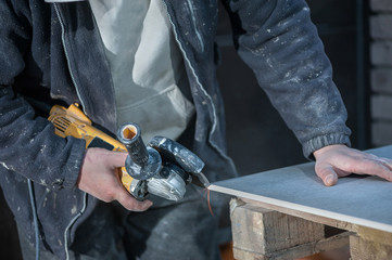Tiler cutting a tile using an angle grinder