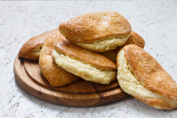 Buns with curd filling. On a wooden board on a white background. Sochni