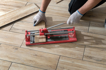 Tiler cutting tiles with tile cutter