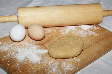 Woman's hands roll out the dough with a wooden rolling pin on a wooden board