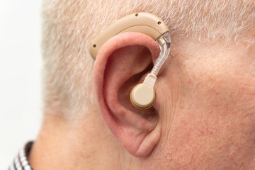 Hearing aid in the ear of aged old man