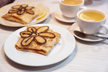 Russian crepes decorated with baked flower with tea 