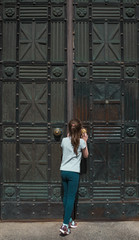 A little curious caucasian girl peeping through a key hole in an old metal door.