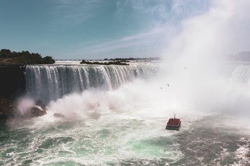 Niagara Falls famous Tour Boat under Horseshoe Waterfall in summer. Horseshoe Fall lies on the border of the United States and Canada