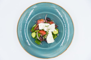 Fresh vegetable salad with cheese on the blue plate. Vegetarian food.