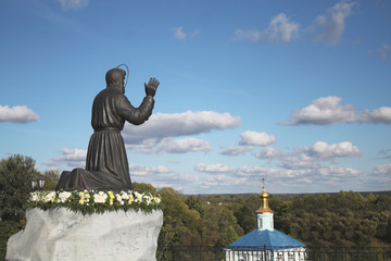 Monument to Seraphim Sorovsky against the background of the Church and the blue sky on a Sunny summer day