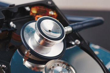Data recovery or computer forensics concept, stethoscope dusty dismantle hard disk over dark background