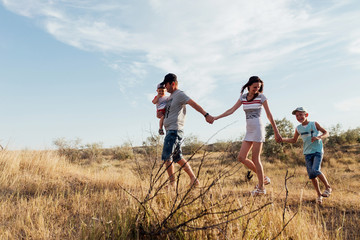 Wide angle portrait of a happy family in the field.