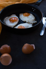 Overhead view of  fried eggs in black baking pan on dark background