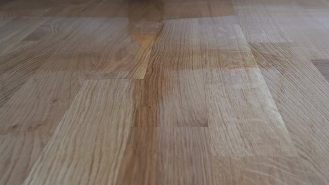 Varnishing lacquering parquet floor by paintbrush - second layer. Home renovation parquet. Varnish paintbrush strokes on a wooden parquet. Application of a highly glossy parquet lacquer