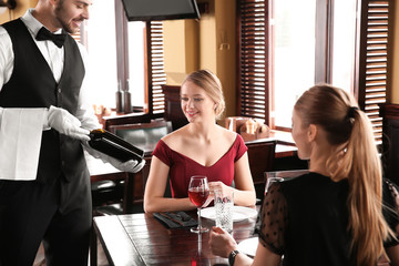 Waiter offering clients bottle of wine in restaurant