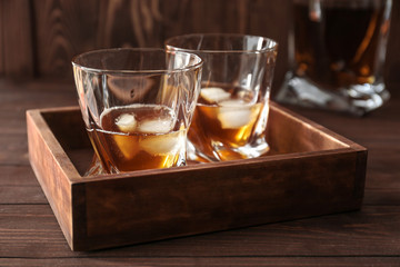 Glasses of cold whiskey on wooden table