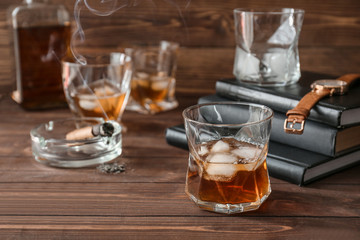 Glass of cold whiskey with cigar on wooden table
