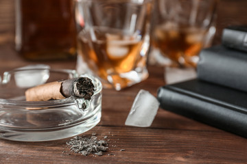 Ashtray with cigar on wooden table