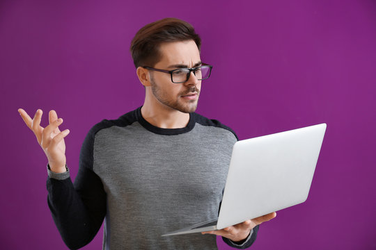 Male programmer with laptop on color background