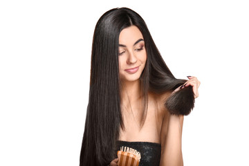 Beautiful young woman brushing her healthy long hair on white background