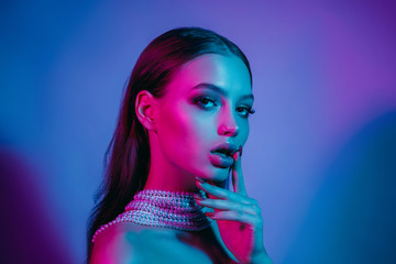 Fototapeta High fashion model in colorful bright neon lights posing at studio. Portrait of beautiful girl with trendy glowing make-up. Art design vivid style. obraz