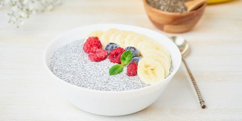 Banner with Chia pudding in bowl with fresh berries raspberries, blueberries. Side view, white wooden light background.