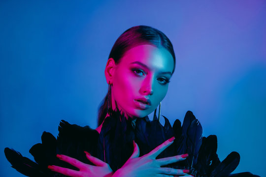 High fashion model in colorful bright neon lights posing at studio. Portrait of beautiful girl with trendy glowing make-up. Art design vivid style.