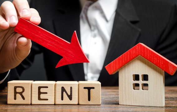 Blocks with the word Rent, down arrow and a miniature house. The concept of reducing the price of renting a house or apartment. Low interest rate. Real estate market. Drop in demand for rental housing