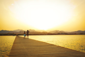 Fototapeta premium A couple on the wood pier at sunset