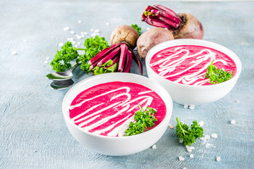 Spring vegetable soup. Homemade beet cream soup, with fresh organic beetroot, sour cream and herbs, blue concrete background copy space