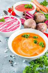Set of various vegetable cream soups, Carrot, beet root, spicy tomato pureed soups with fresh organic veggies, blue concrete background, copy space
