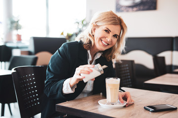 Frau im Cafe süßt ihren Kaffee mit Zucker 