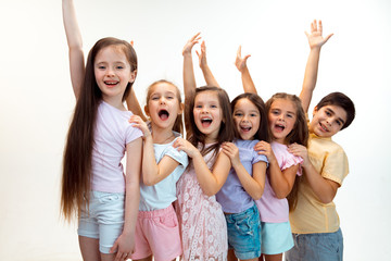 The portrait of happy cute little kids boy and girls in stylish casual clothes looking at camera against white studio wall. Kids fashion and human emotions concept