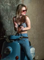 Fototapeta na wymiar Beautiful young girl in a bodice and jeans in on a scooter