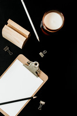 Empty paper blank clipboard, pencil, candle and clips on black background. Flatlay, top view minimal office workspace.
