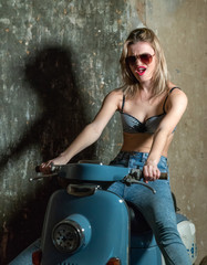 Fototapeta na wymiar Beautiful young girl in a bodice and jeans in on a scooter