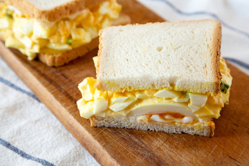 Homemade egg sandwich for breakfast on rustic wooden board, side view. Close-up.