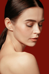 Fototapeta premium A beautiful female face. Perfect and clean skin of young caucasian woman on red studio background.