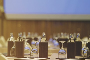 Image close up environmental of White paper with pencil and glass with bottled water setup on the table for the speech of the lecture ,Prepare conference in the hotel. Processed color tone.