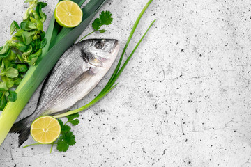 Raw fresh dorada fish with herbs, onion and lime ingredients for cooking on white background, Top view and copy space. Mediterranean healthy food concept