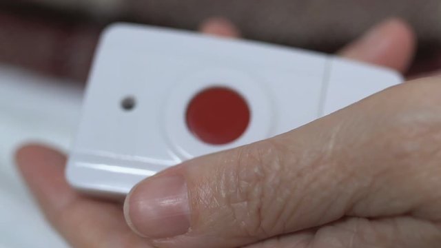 Close-up of aged female patient pushing red button, calling nurse for help