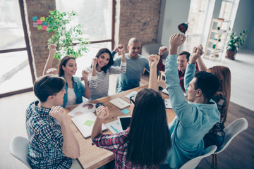 Fototapeta premium Excited delighted managers partners professionals champions after brainstorming having training seminars aims gesturing raising fists sitting at desk office