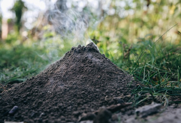 Small burning volcano. Smoke from the pile of ground. Nature outdoors.