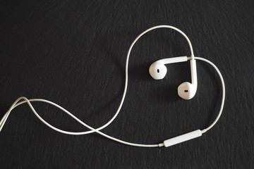 white wired headphones on a black textural background.
