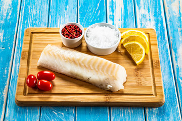Fresh raw cod served on cutting board on wooden table