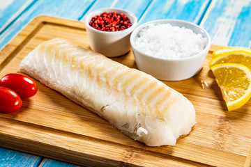 Fresh raw cod served on cutting board on wooden table