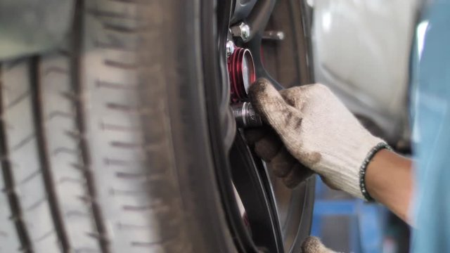 Auto mechanic working on brakes in a car repair shop domestic garage. Professional repair of a car.