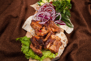 grilled barbecue meat served on a wooden Board with fresh vegetables and spices