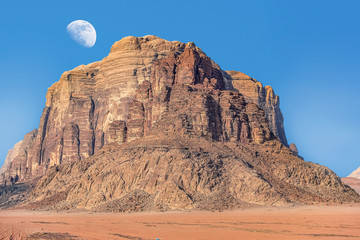 Fototapeta premium incredible lunar landscape with huge moon in Wadi Rum village in the Jordanian red sand desert. Wadi Rum also known as The Valley of the Moon, Jordan - Image