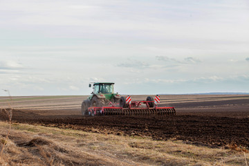 Fototapeta premium Agriculture,tractor preparing land with seedbed cultivator as part of pre seeding activities in early spring season of agricultural works at farmlands
