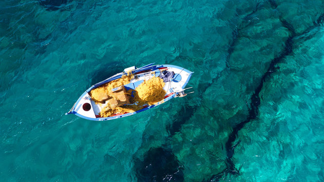 Aerial photo from traditional picturesque fishing boat on turquoise clear sea as seen from top in island of Paros, Cyclades, Greece